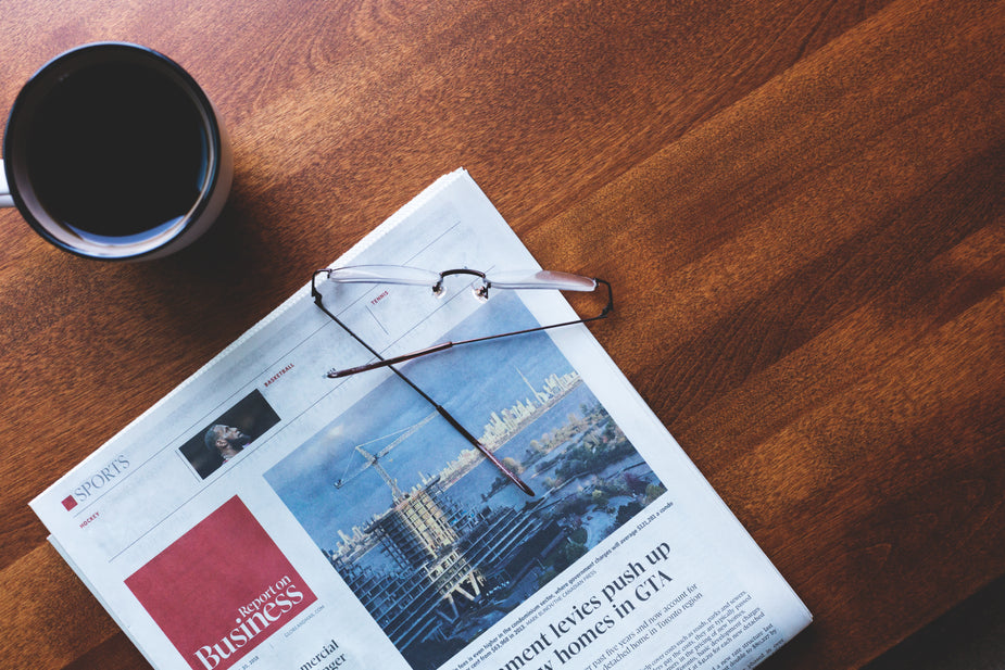 Coffee cup, news paper and glasses on a table