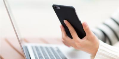 A person holding a smartphone and taking notes