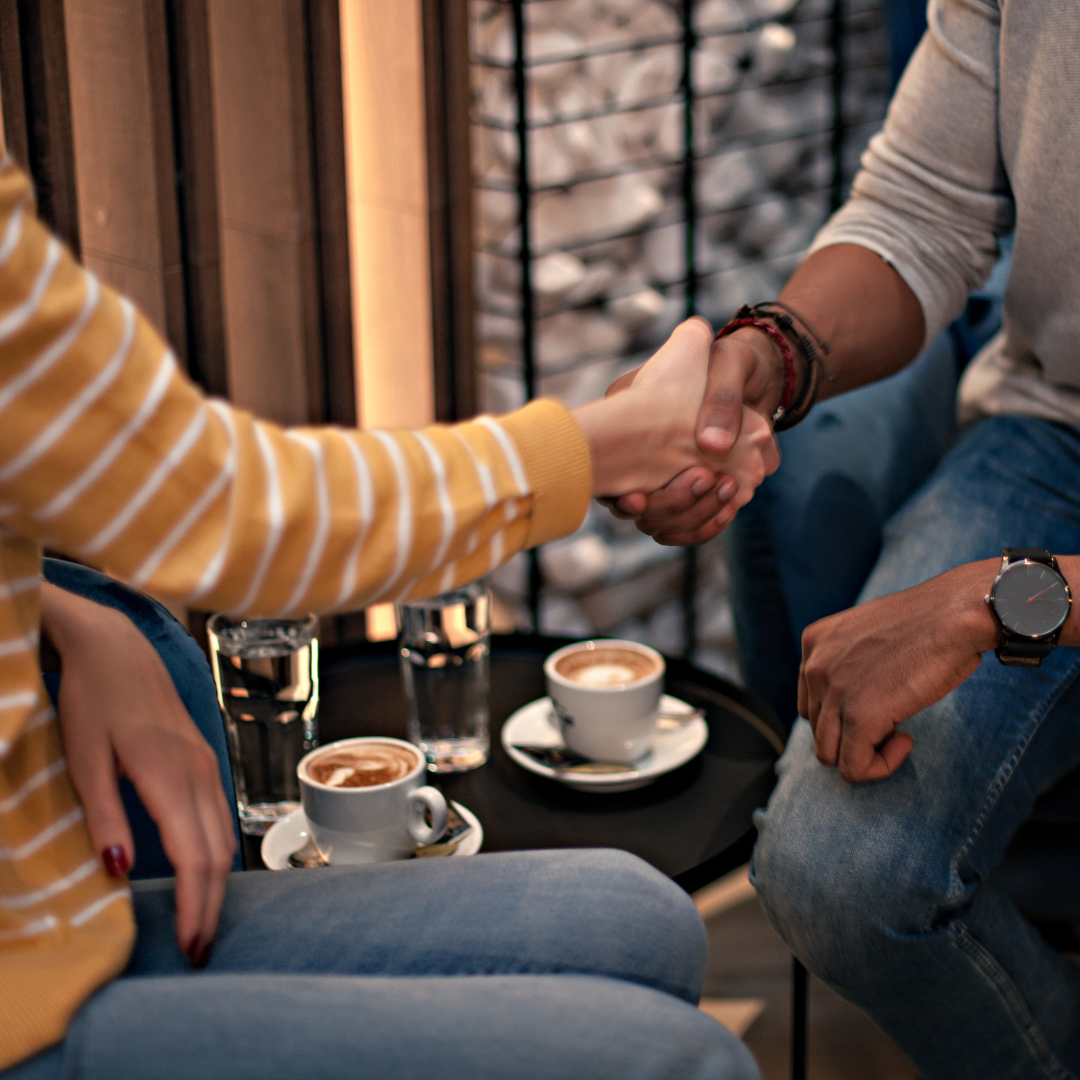 Two people shaking hands over coffee