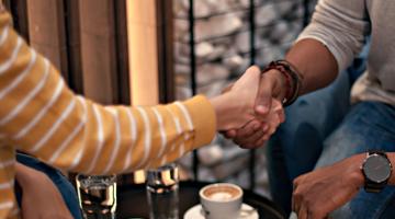 Two people shaking hands over coffee